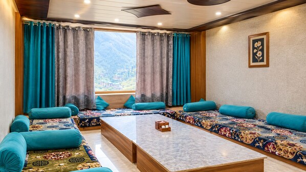A room with a sofa set, a coffee table, and a view of mountains through a window.