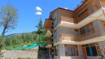 A multi-story building with balconies and a view of mountains.