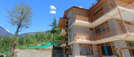A multi-story building with balconies and a view of mountains.