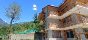 A multi-story building with balconies and a view of mountains.