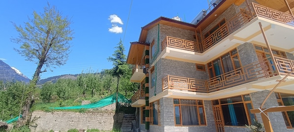 Un edificio de varios pisos con balcones y vista a las montañas.