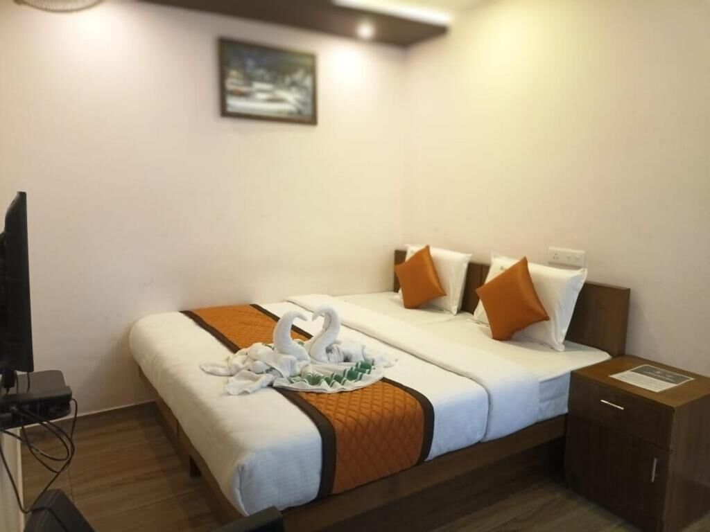 A hotel room with a bed, pillows, a tray with swans, a television, and a cabinet.