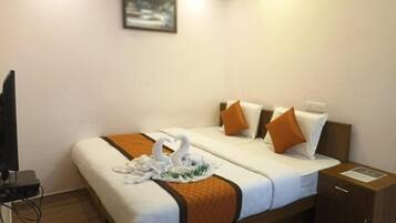 A hotel room with a bed, pillows, a tray with swans, a television, and a cabinet.