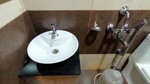 Un bany amb un rentapans blanc, un mirall, un suport de tovalloles i una zona de dutxa.