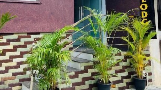 Un edifici amb façana moderna, un senyal vertical destacat amb el text 'MAJESTIC LODGE' i plantes en testos a la façana.