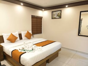 Habitación de hotel con cama, almohadas, manta, toalla, ventana con persianas, un cuadro en la pared y un espejo.