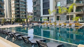Un hotel moderno con piscina, sdraio e un giardino curato.