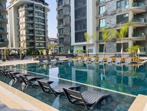 Ein modernes Hotel mit Schwimmbad, Liegestühlen und einem gepflegten Garten.
