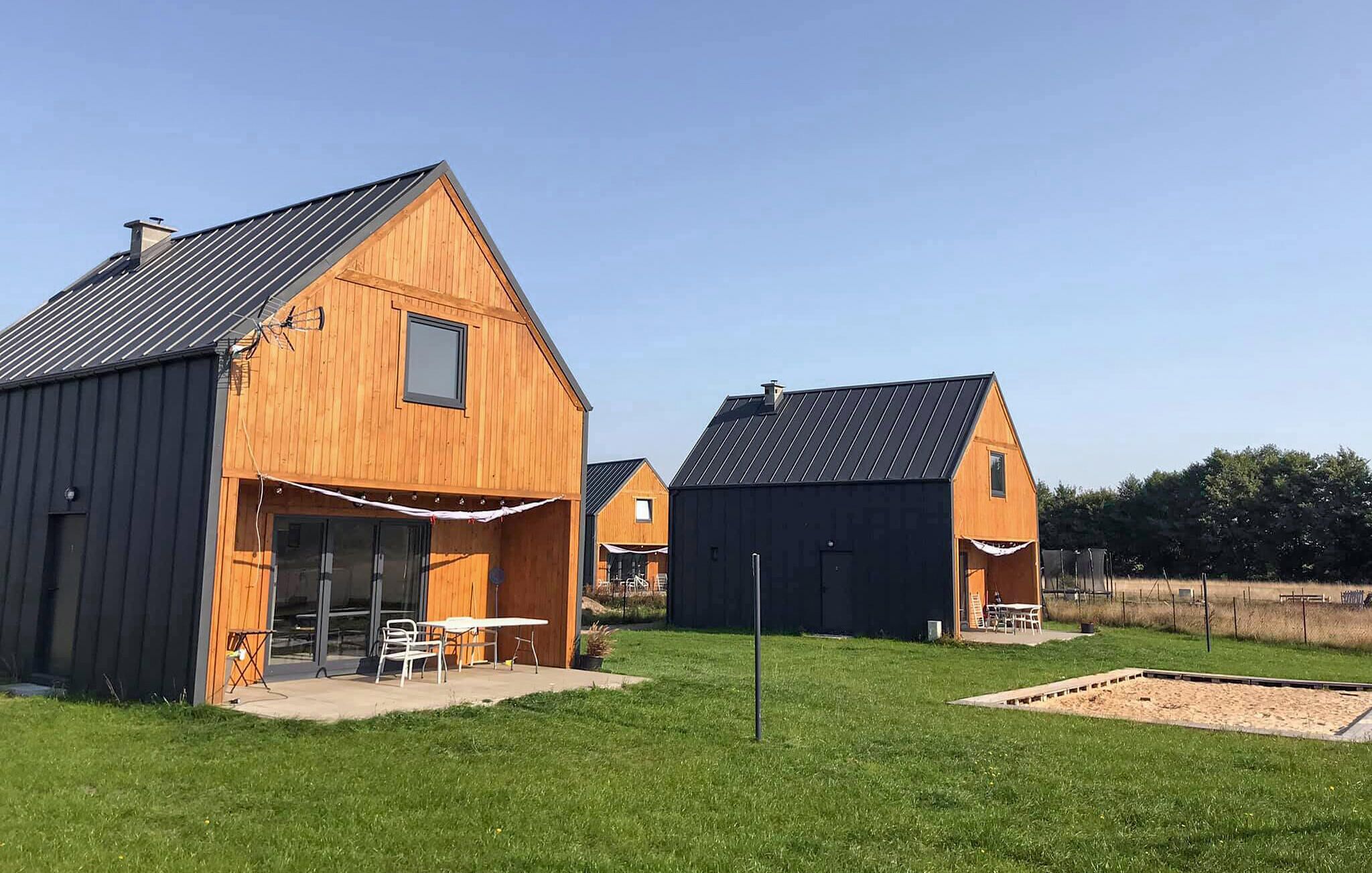 Een houten schuurstijlgebouw met een overdekt terras en een tafel met stoelen buiten.