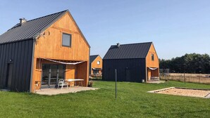 Un bâtiment en bois de style grange, doté d’un patio couvert et d’une table et de chaises installées à l’extérieur.