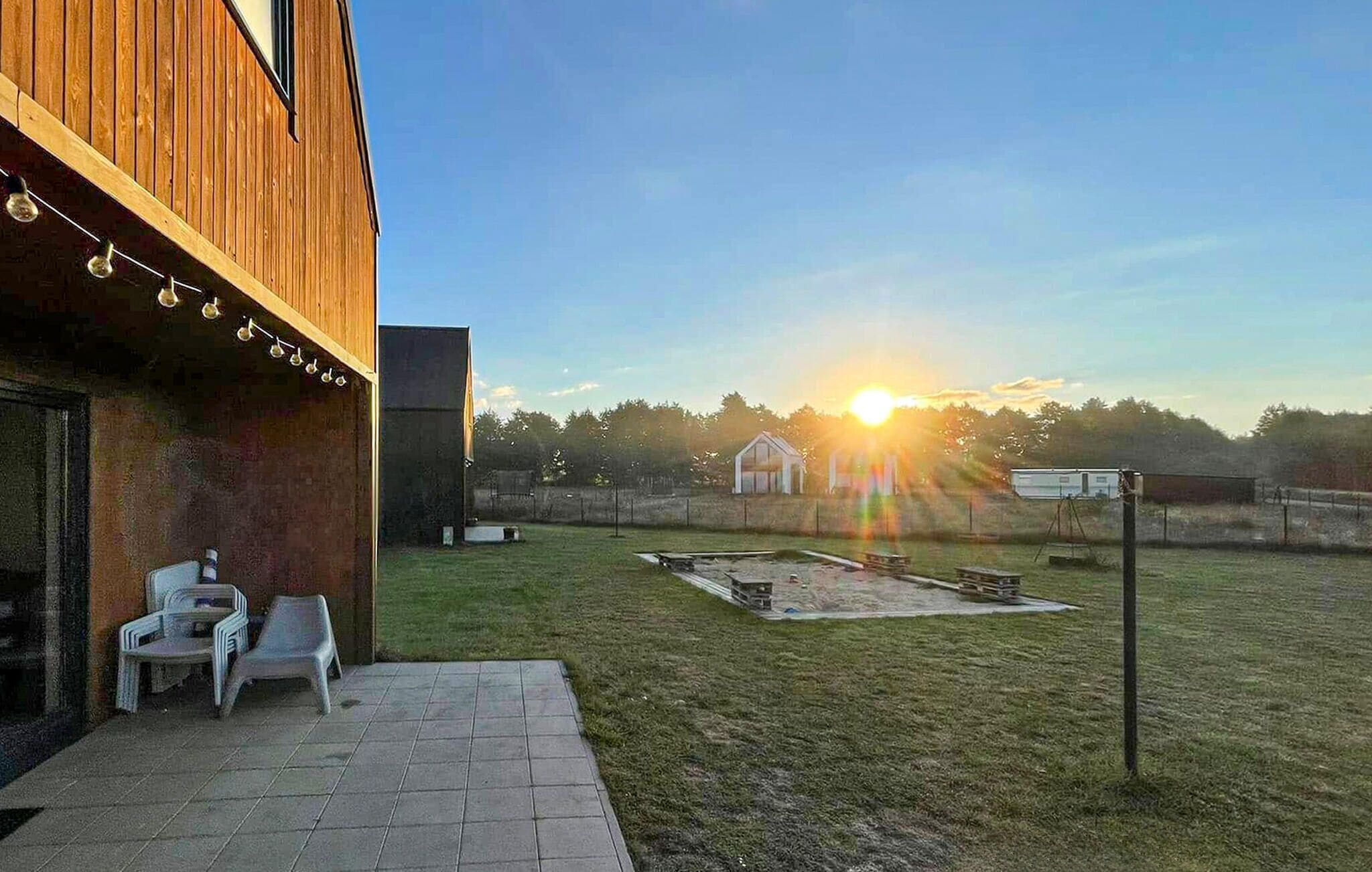 A patio area with a wooden building, a small garden, and a clear sky.