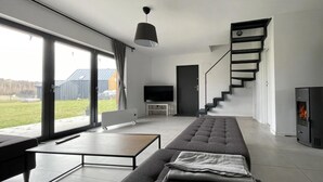 Un salon moderne avec un canapé, un téléviseur, une cheminée et un escalier.