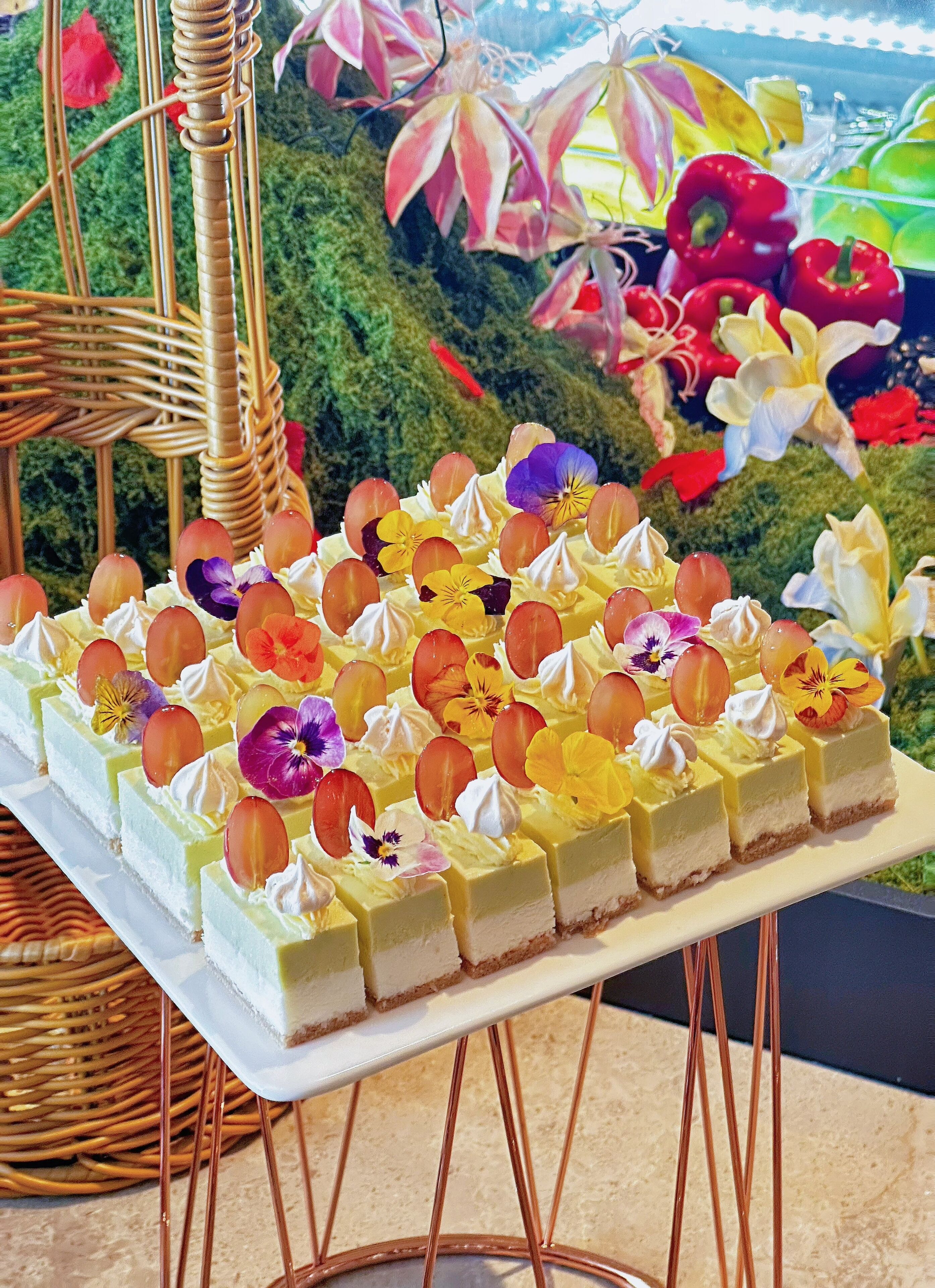 A tiered dessert display with various fruits and flowers.