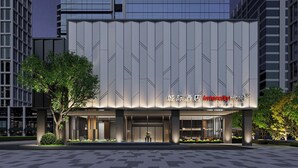 Un hotel moderno con fachada geométrica, ventanas amplias y una entrada bien iluminada.