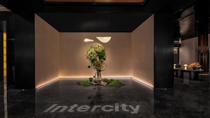 Un moderno vestíbulo con una recepción, un centro de mesa con planta decorativa y un piso de mármol pulido.