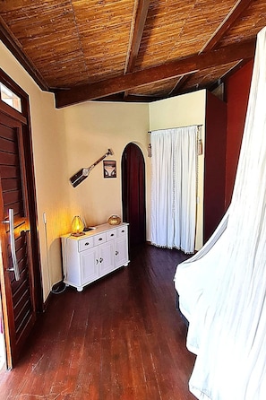 Ein Zimmer mit Holzboden, einem weißen Schrank, einer Tür und einem Vorhang.
