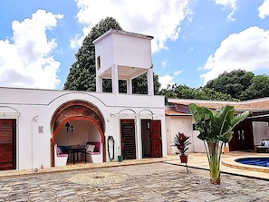 Ein Gebäude mit weißer Fassade, einer überdachten Terrasse und einem Swimmingpool.