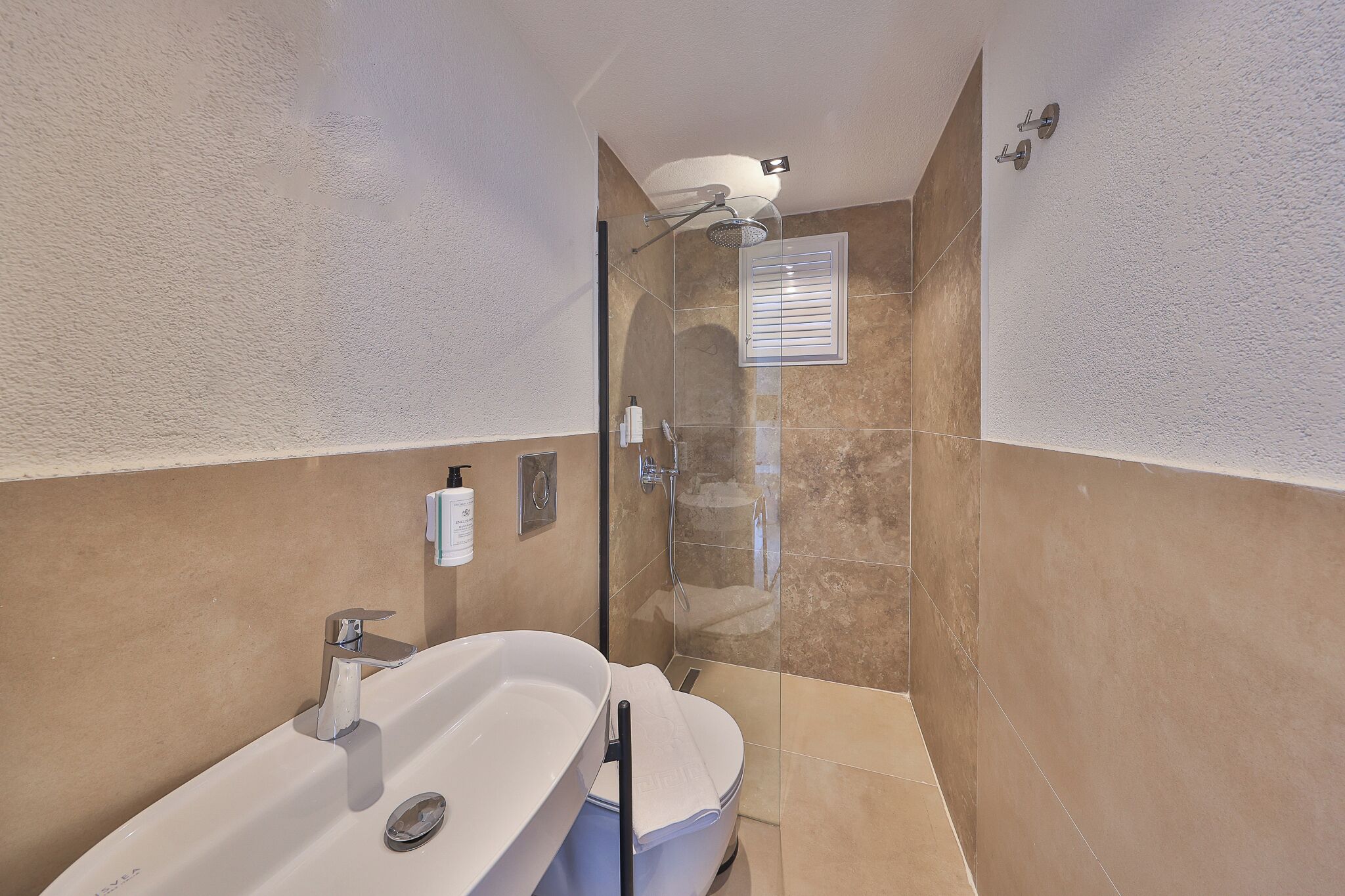 Une salle de bain moderne dotée d’une grande baignoire, d’une douche et d’un espace de douche séparé par des parois en verre.