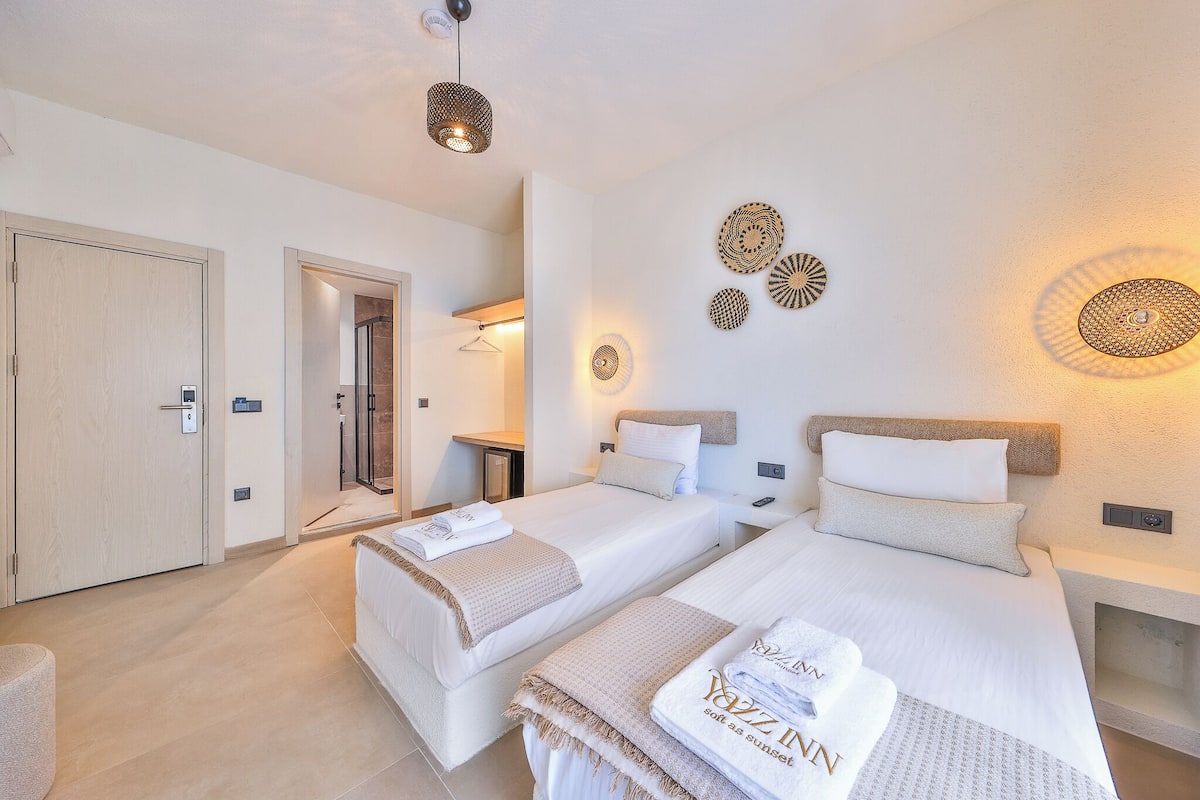 A hotel room with two beds, a shower, a small table, and wall decor.