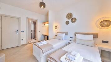 A hotel room with two beds, a shower, a small table, and wall decor.