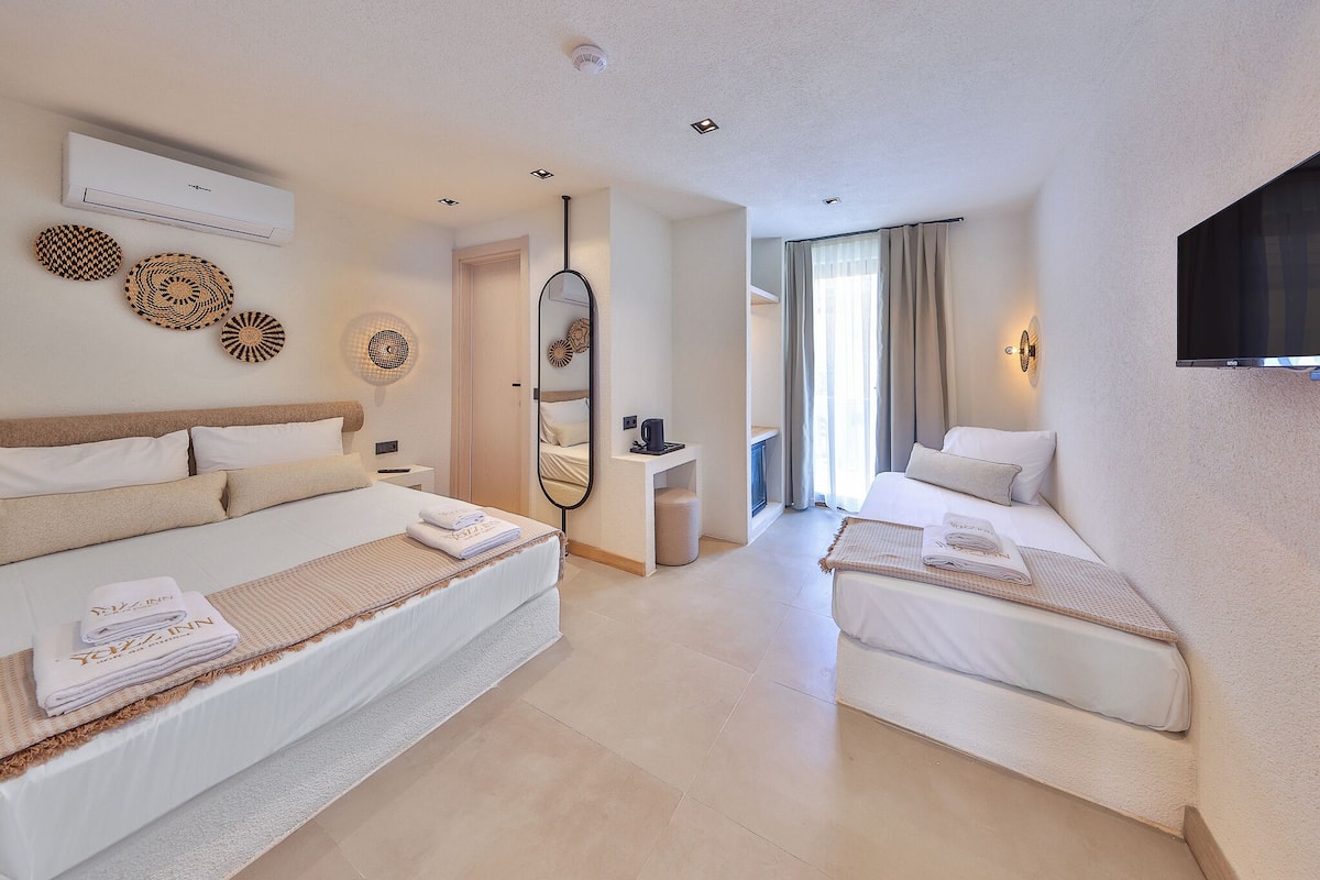 A hotel room with two beds, a TV, a mirror, and a small table.