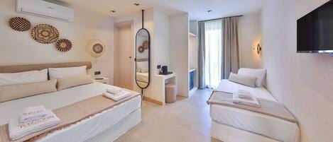 A hotel room with two beds, a TV, a mirror, and a small table.