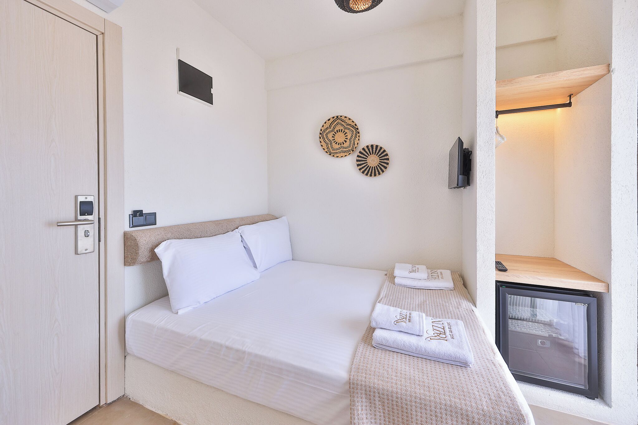 Habitació d'hotel amb llit, una petita taula de treball amb un ordinador, televisió i nevera.