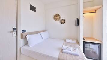 Habitació d'hotel amb llit, una petita taula de treball amb un ordinador, televisió i nevera.