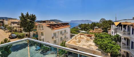 A residential area with a clear view of the sea, a balcony with outdoor furniture, and a building with a partially constructed roof.