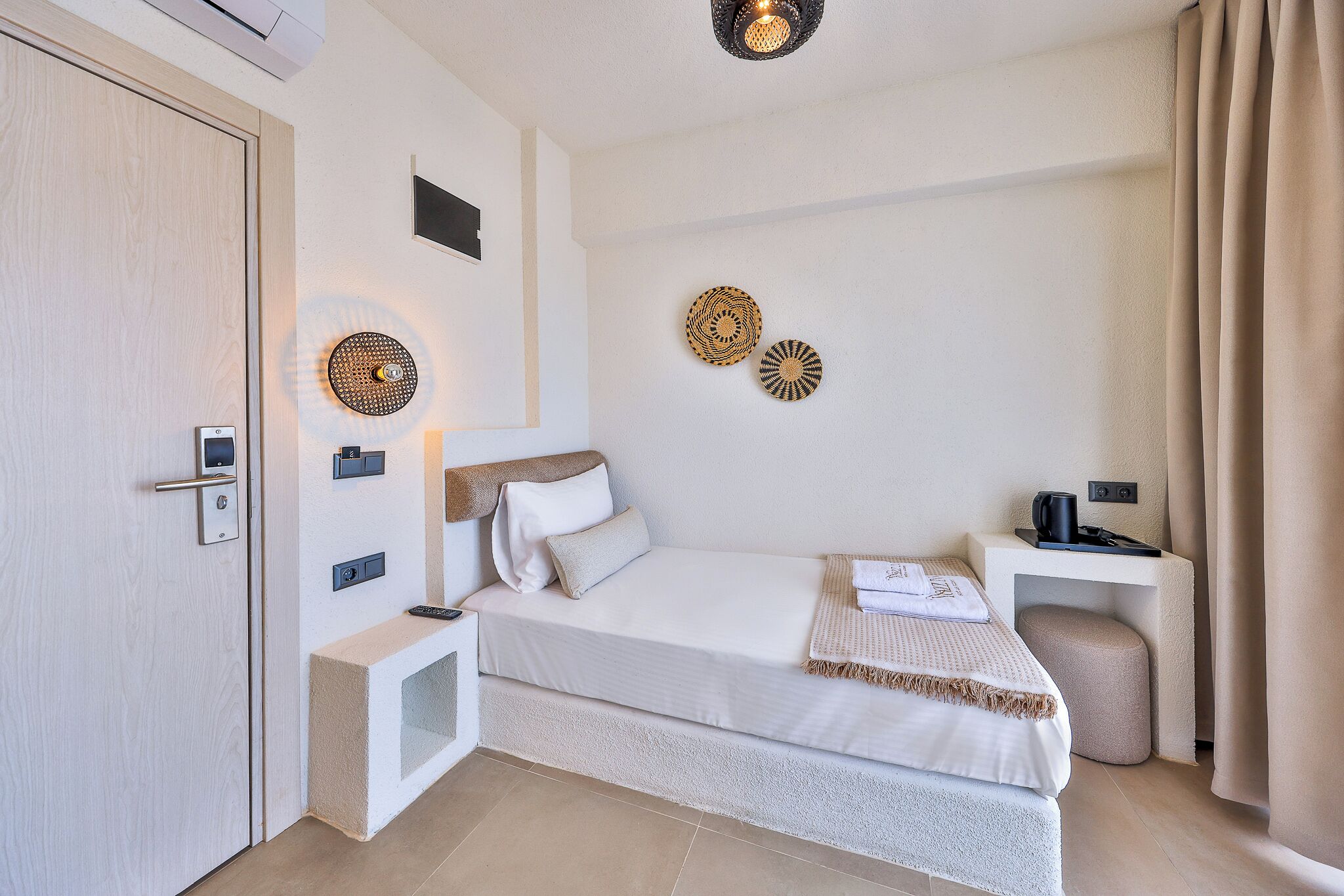 Una habitación de hotel moderna con una cama, una mesita de noche, decoración en la pared y una puerta.