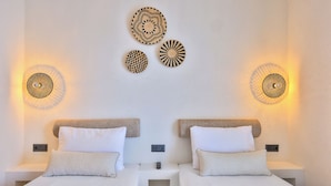 A hotel room with two beds, a small table, and wall-mounted light fixtures.