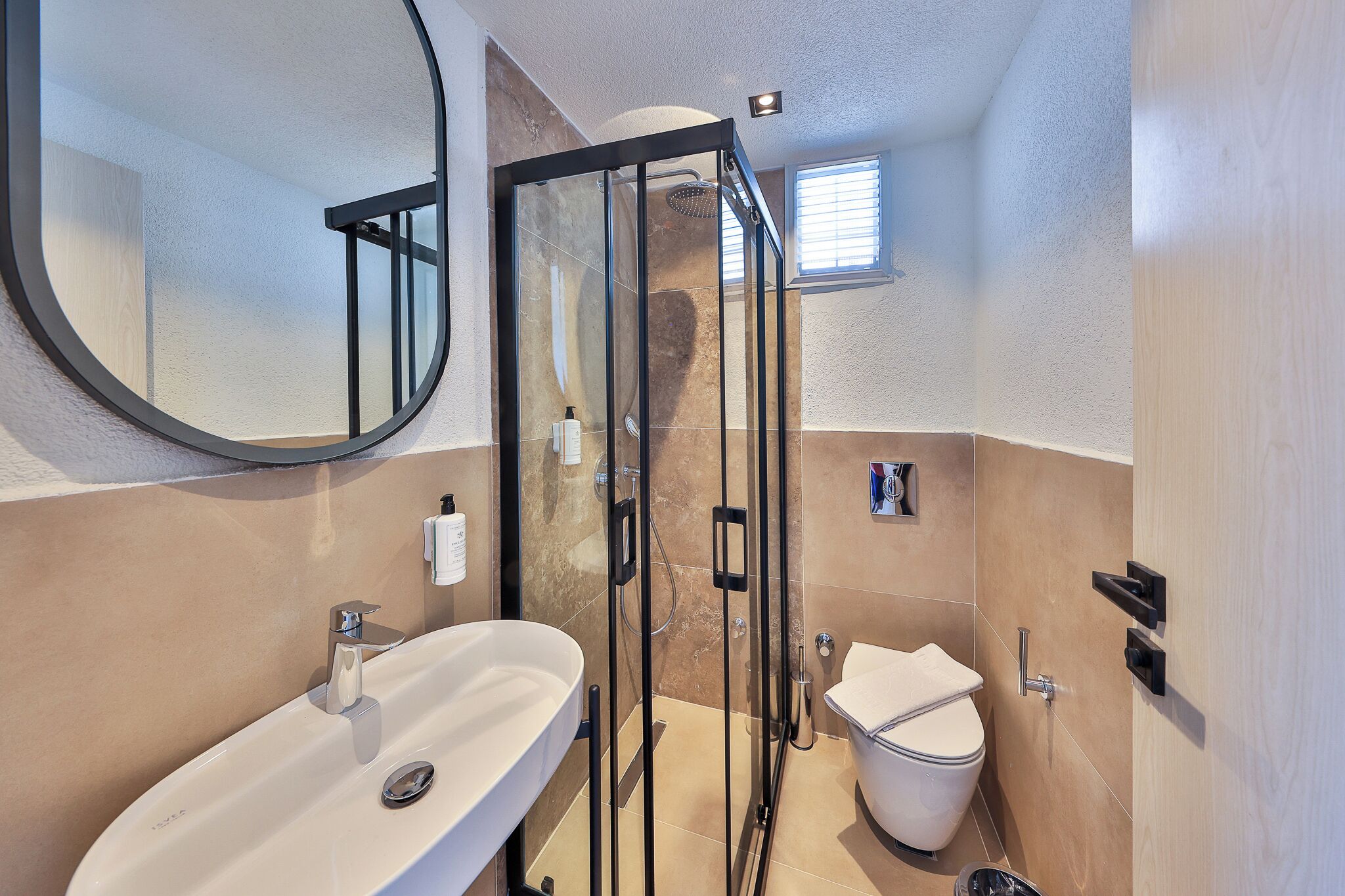 Un baño con ducha de vidrio, lavamanos e inodoro.