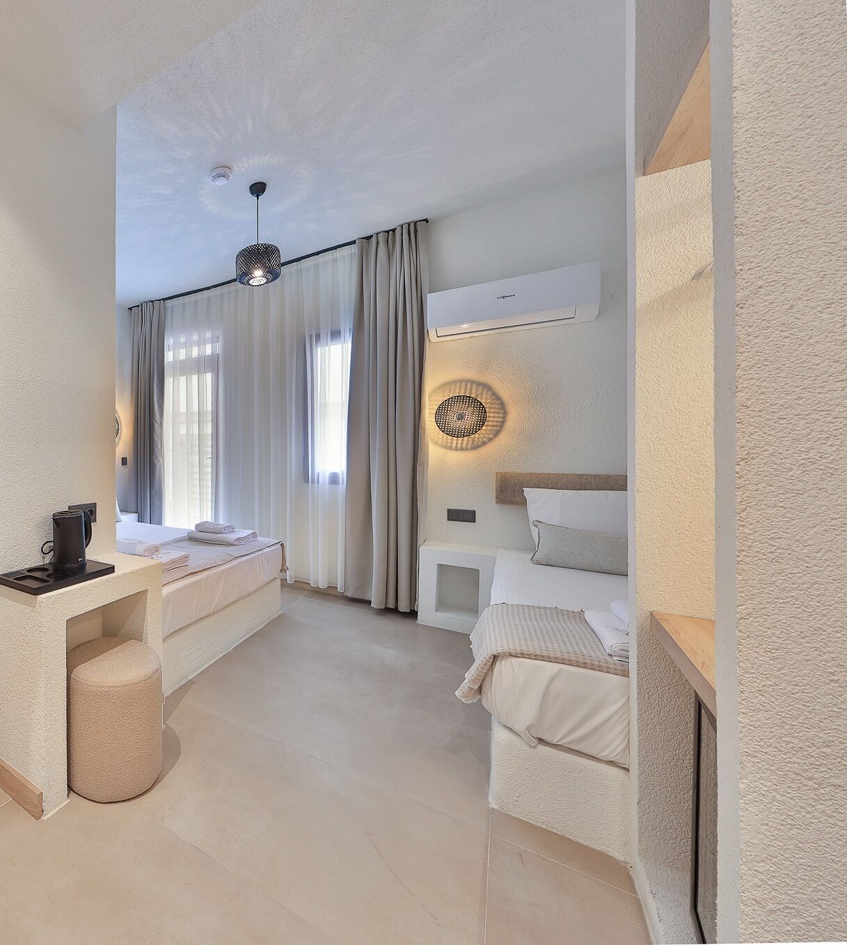 A modern hotel room with a bed, bedside tables, a desk, and a large window with curtains.