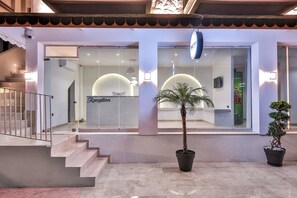 L'ingresso di un hotel con una reception, una scala e piante in vaso.