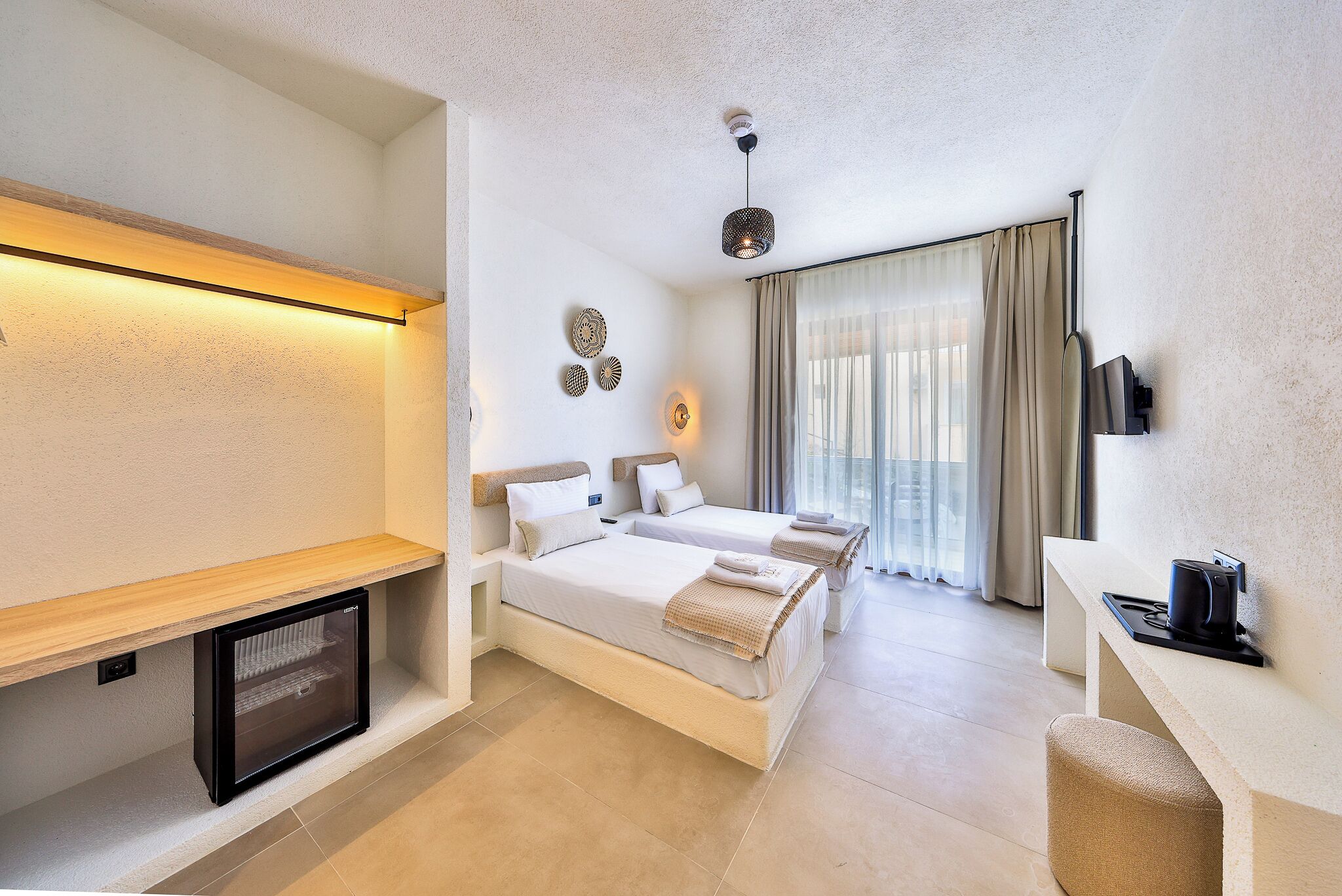 A hotel room with a bed, bedside table, TV, and a small seating area.