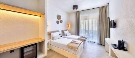 A hotel room with a bed, bedside table, TV, and a small seating area.