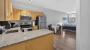 Eine moderne Küche mit Granit-Arbeitsplatten, Holzschränken und Edelstahlgeräten, sowie ein Essbereich mit Tisch und Stühlen.