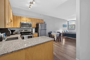Eine moderne Küche mit Granit-Arbeitsplatten, Holzschränken und Edelstahlgeräten, sowie ein Essbereich mit Tisch und Stühlen.