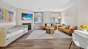 Ein modernes Wohnzimmer mit einer Couch, zwei Sesseln, einem Couchtisch und einem Kamin.