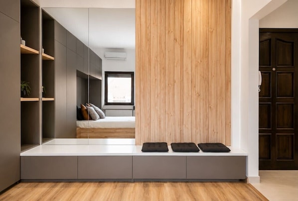 Ein modernes Interieur mit eingebauter Bank, einer Holzvertäfelung und Blick in ein Schlafzimmer mit Bett und Kissen.