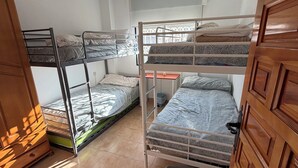Ein Schlafraum mit Etagenbetten, einem Holzschrank, einem Fenster und einer Deckenleuchte.