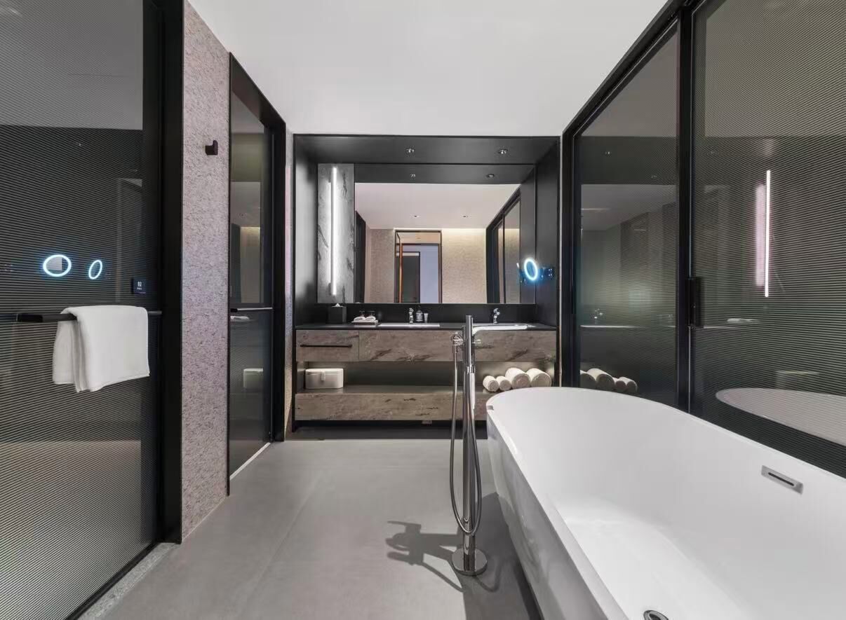 A modern bathroom with a large bathtub, a double sink vanity, and a glass-enclosed shower area.