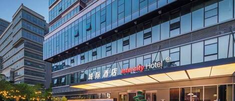 A modern hotel building with a prominent Intercity Hotel sign, large windows, and a well-lit entrance.