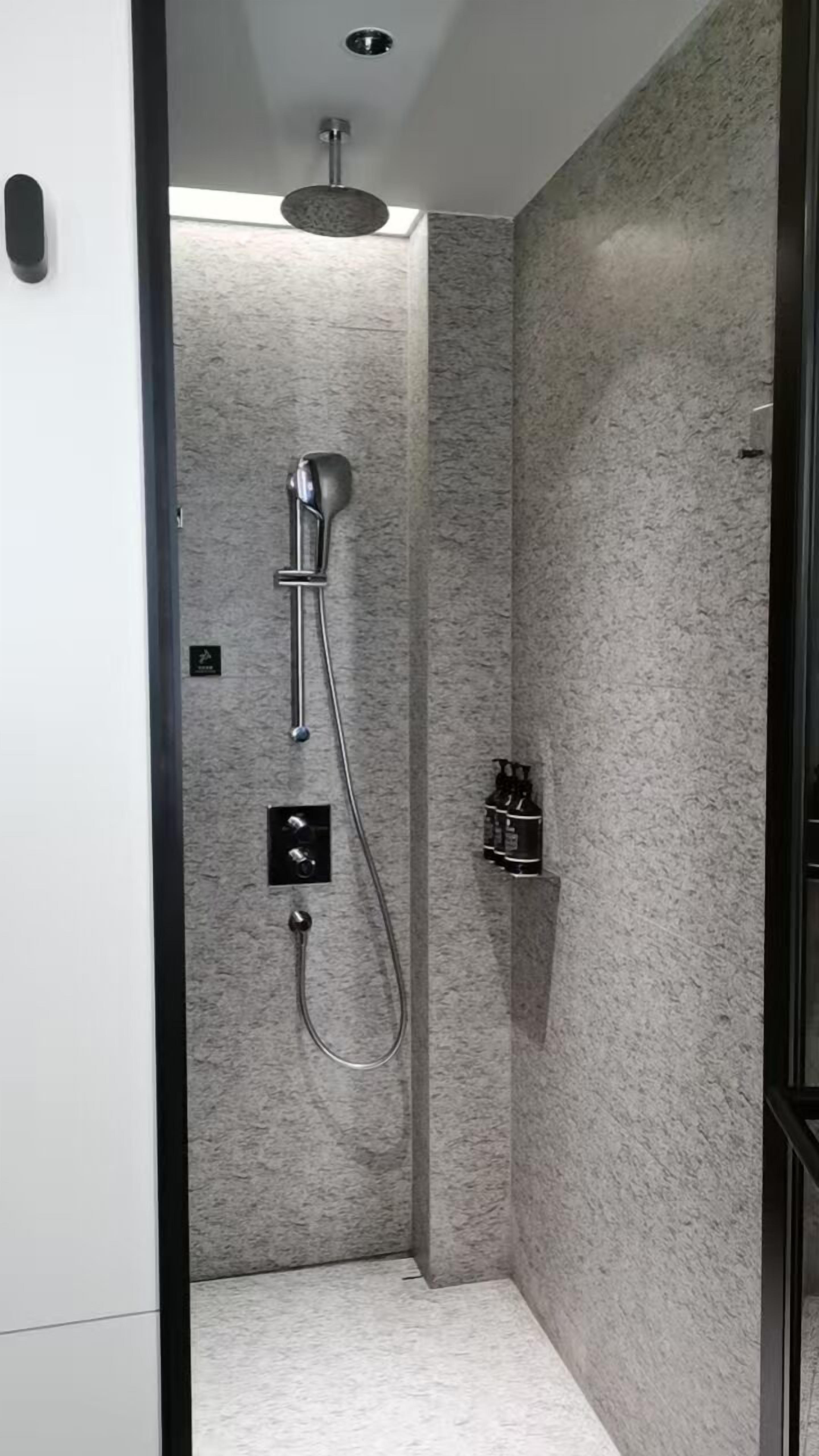 A modern shower with a handheld showerhead and a wall-mounted faucet.