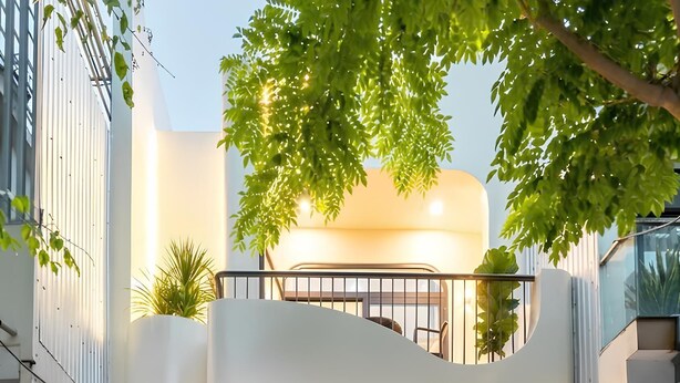 A modern building with a large wooden door, a balcony with a railing, and a window with a view of trees. - Hometown Nimi 3 BRS Pool Villa Da Nang (Da Nang)
