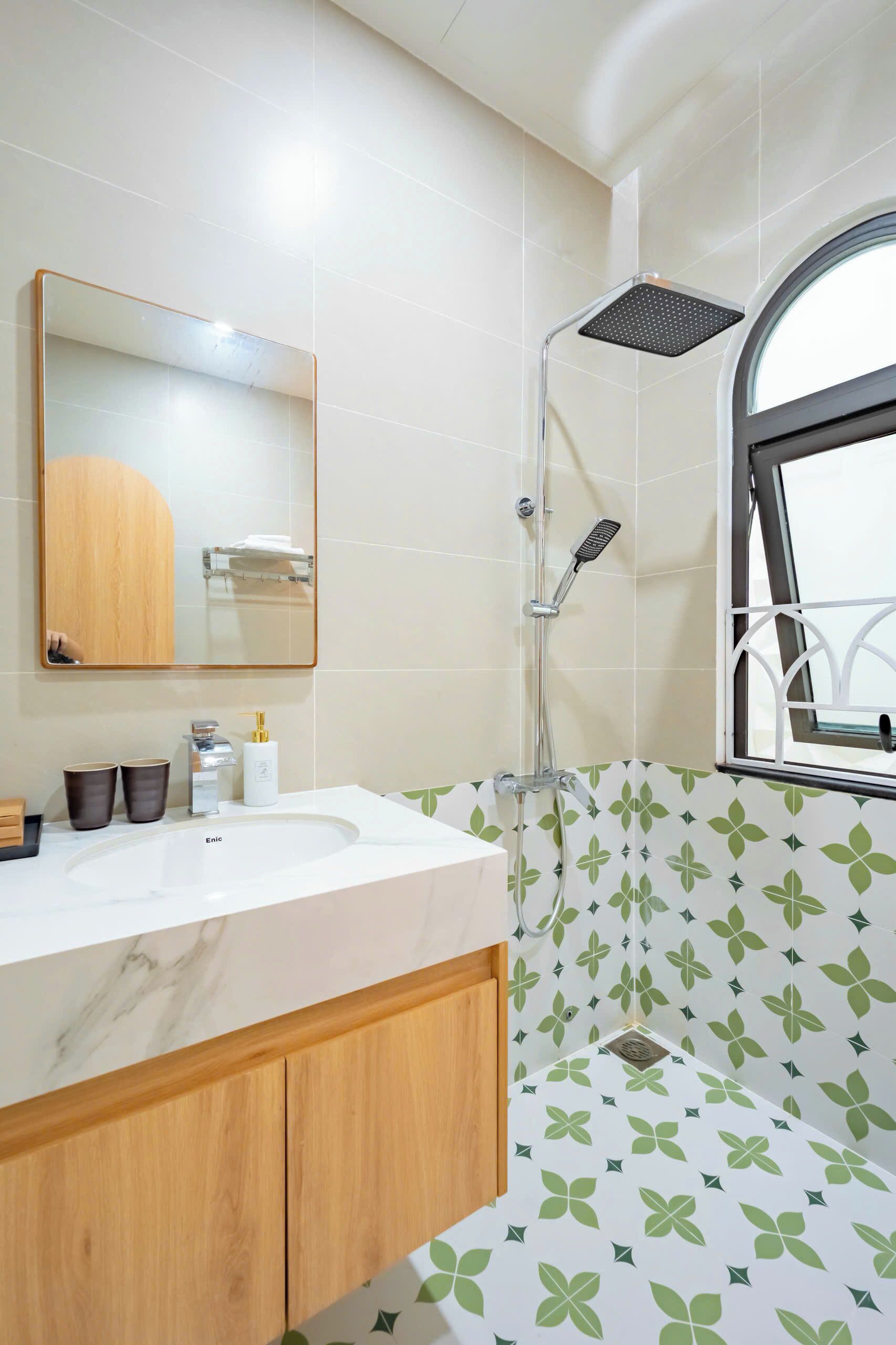 A bathroom with a shower, a sink, a mirror, and a window.