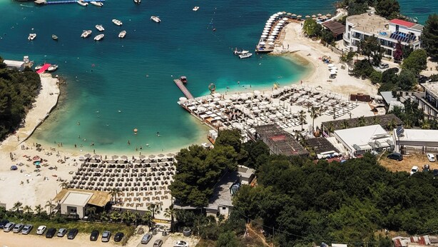 An aerial view of a coastal area with a beach, boats, and a marina. - Luxury Villa Oasis (Ksamil)