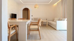 A modern living room with a sofa, chairs, a small table, and a TV. - Luxury Villa Oasis (Ksamil)