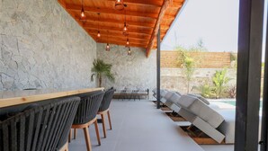 A bar area with stone walls, wooden ceiling, and seating. - Luxury Villa Oasis (Ksamil)
