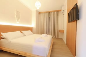 Een hotelkamer met een bed, gordijnen, een bevestigde televisie en een wandairconditioner.